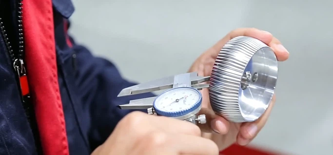 CNC machinist at Dazao checking standard machining tolerances on a custom milled Al6061 part using a digital micrometer CNC machinist at Dazao checking standard machining tolerances on a custom milled Al6061 part using a digital micrometer